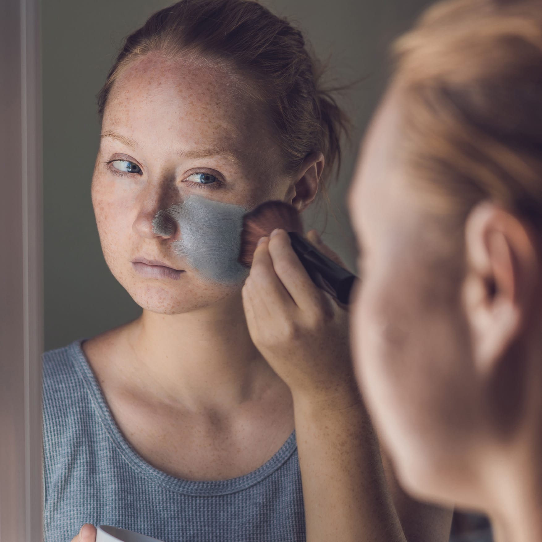 Spa Woman applying Facial green clay Mask. Beauty Treatments. Close-up portrait of beautiful girl applying facial mask virtual skincare facials